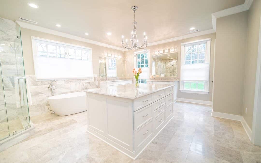 Luxury master bathroom with central vanity island, bathtub, and chandelier.