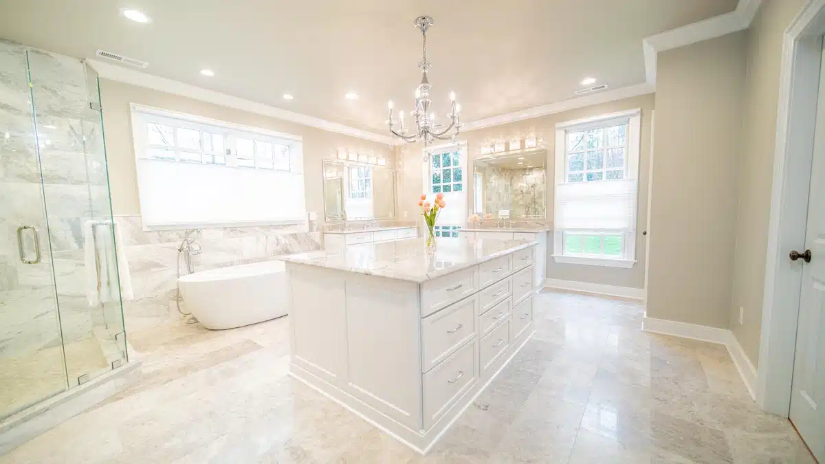 Luxury master bathroom with central vanity island, bathtub, and chandelier.