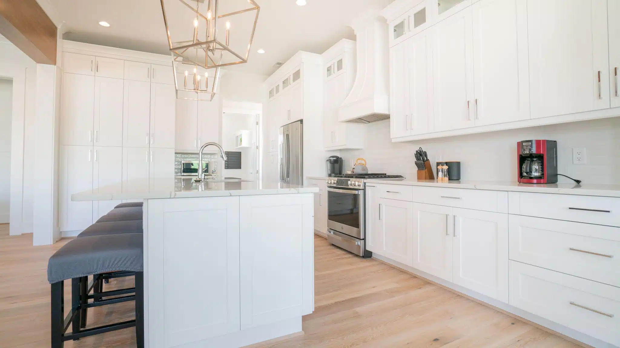 Chef’s kitchen with custom cabinetry, quartz countertops, oversized island, stainless appliances, and designer lighting