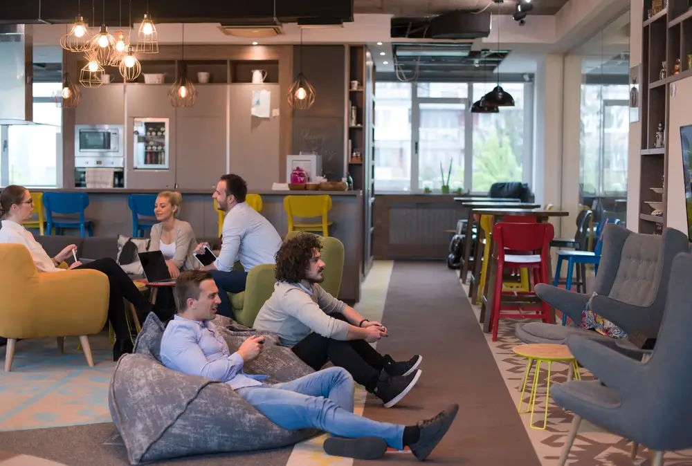 Employees relaxing in a modern office lounge area with beanbags.