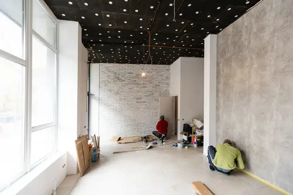 Workers renovating a modern open-concept office interior space.